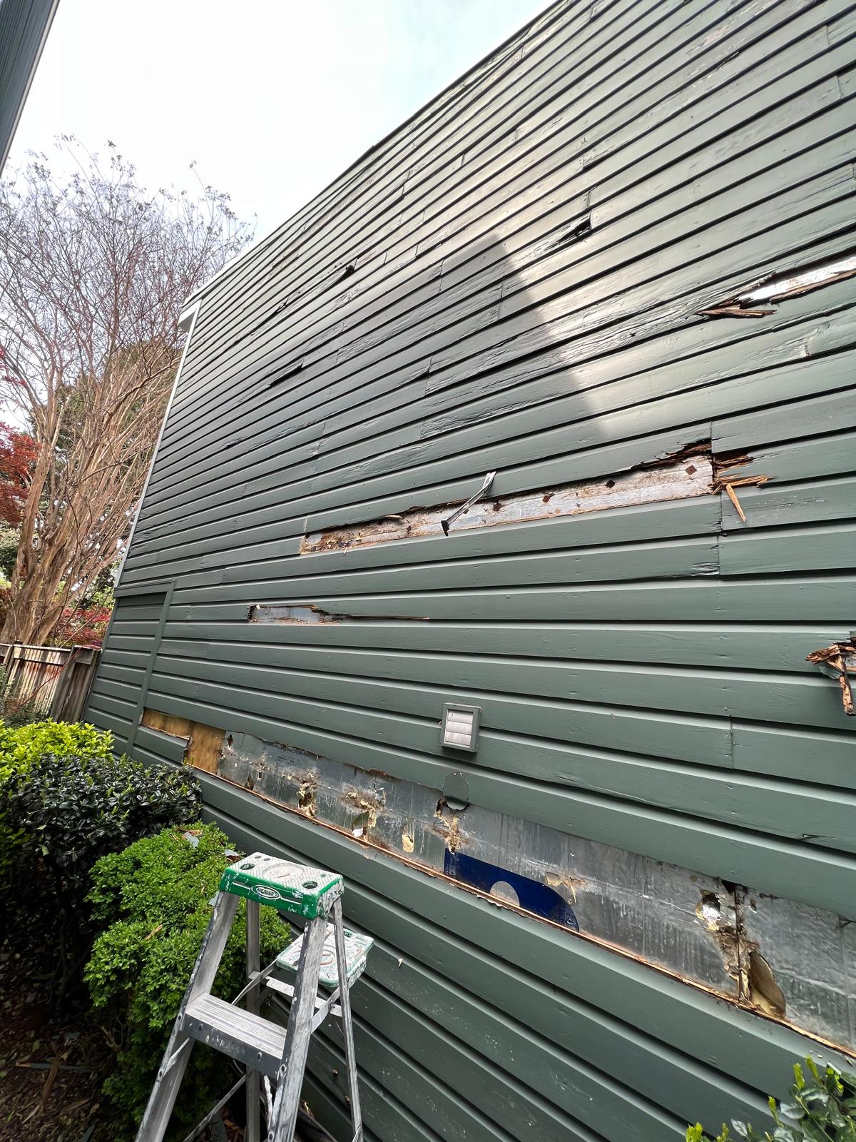 Wider view of damaged exterior siding before the replacement work.