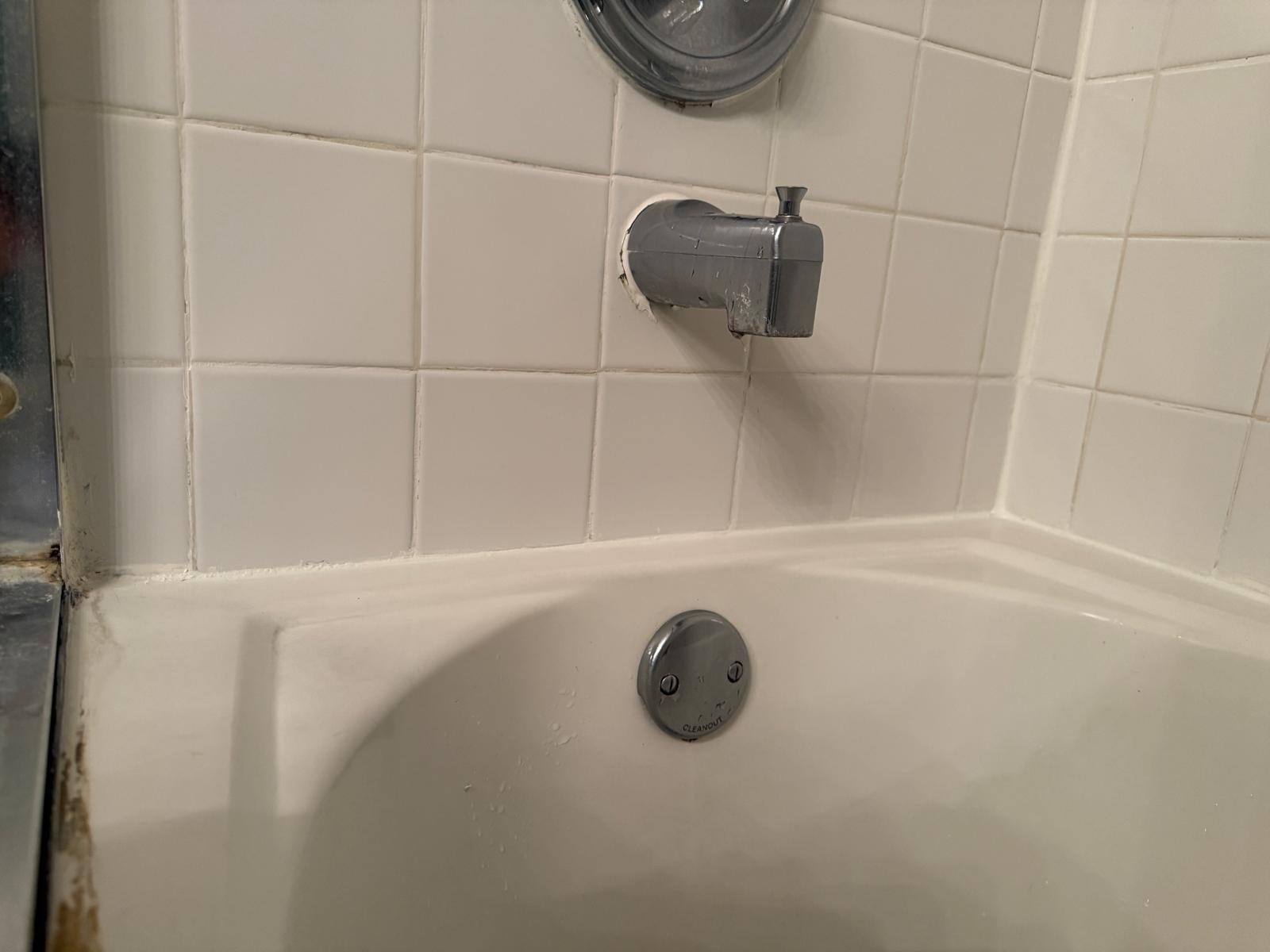 White wall tiles and bath fittings before the local repair.