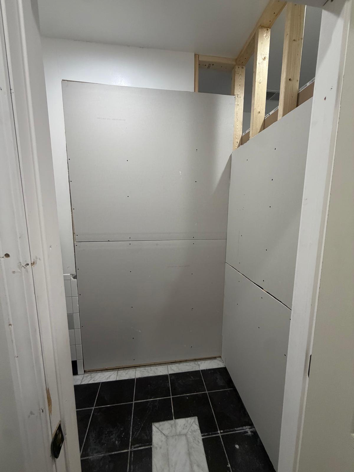 Same closet viewed through its doorway with plasterboard fixed to the new partitions.
