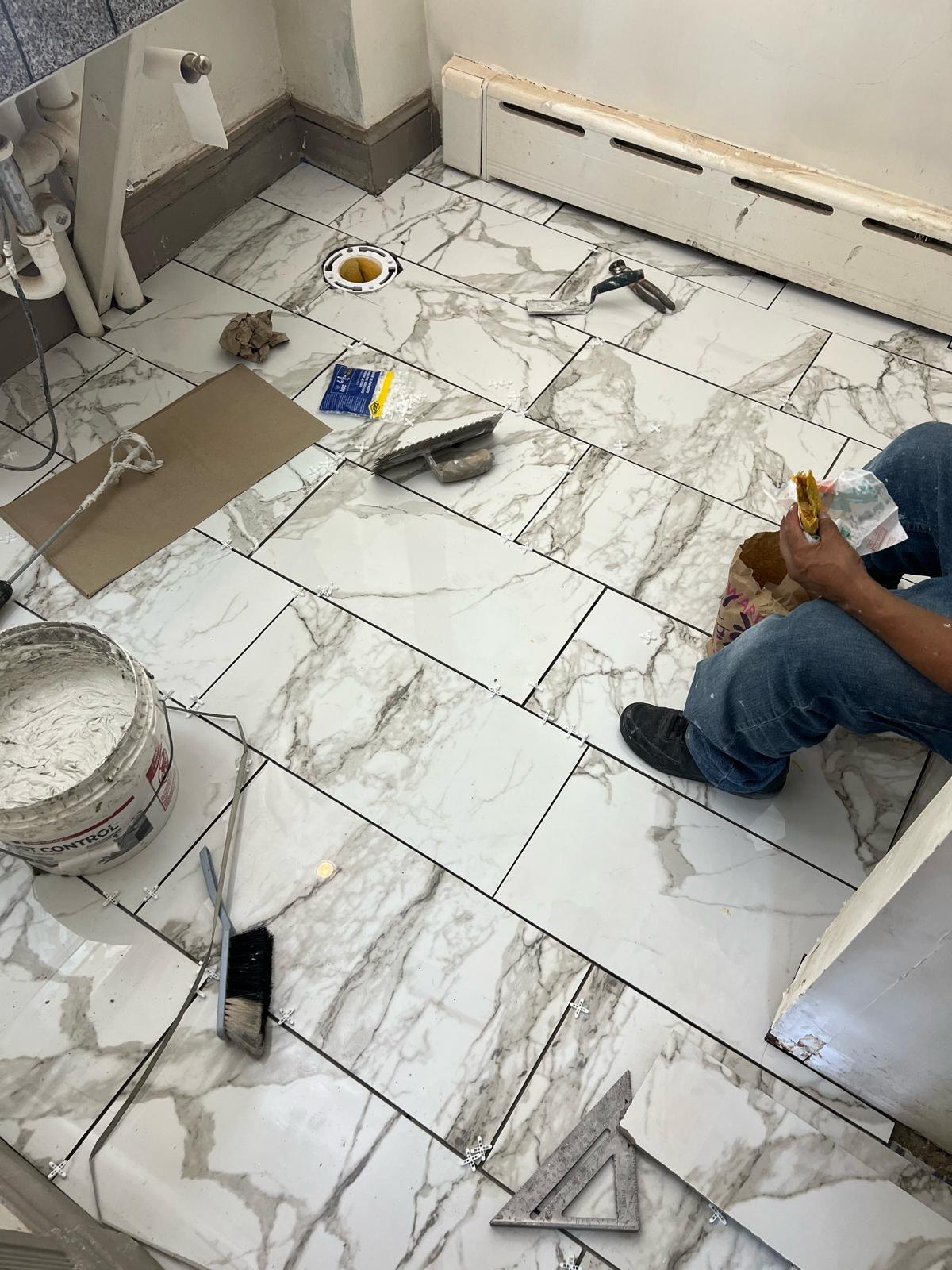 Marble-pattern floor tiles with spacers and tools, before the toilet is refitted.