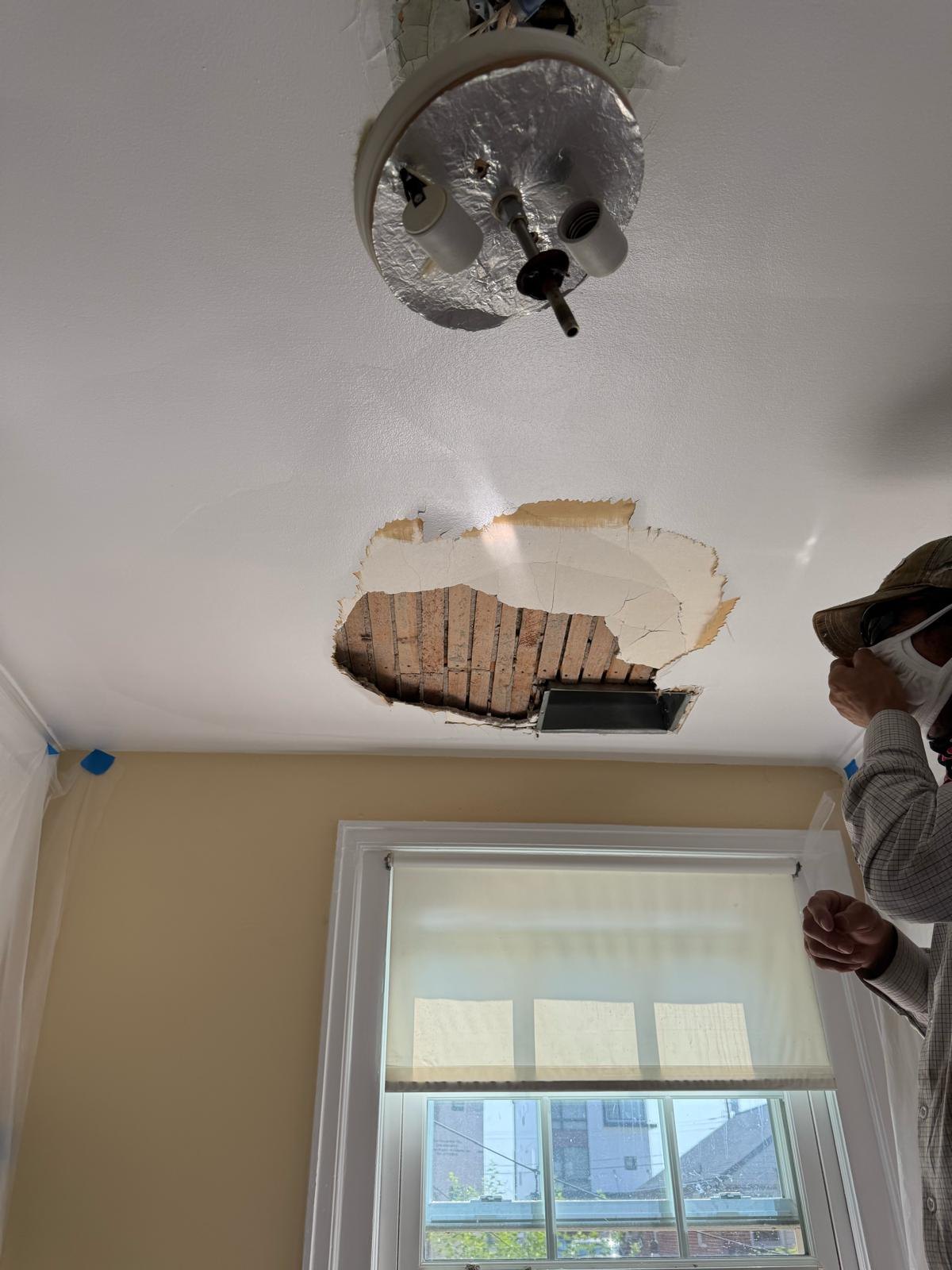 Ceiling with damaged plaster opening before drywall work.