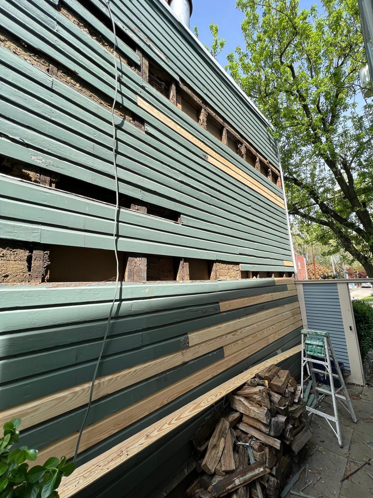 Open sections in the siding with replacement timber fitted below.