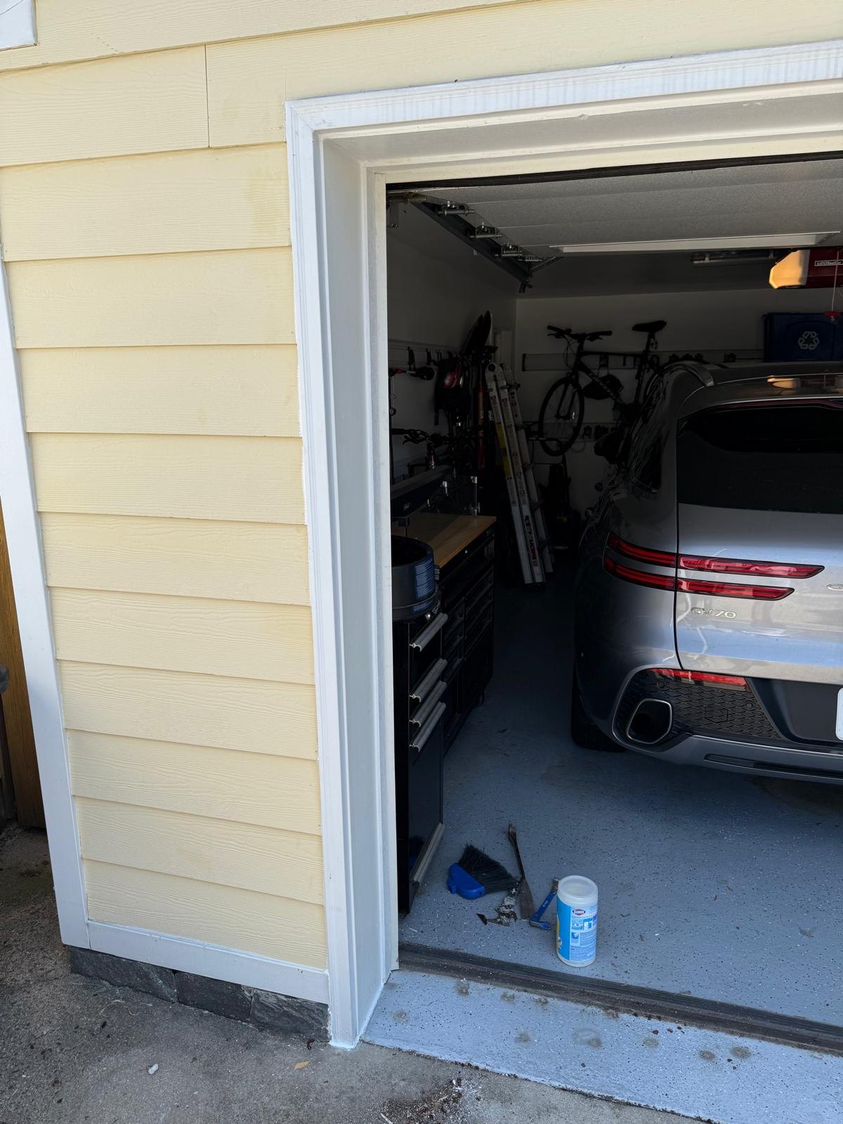 White replacement trim fitted around the garage opening beside the retained siding.