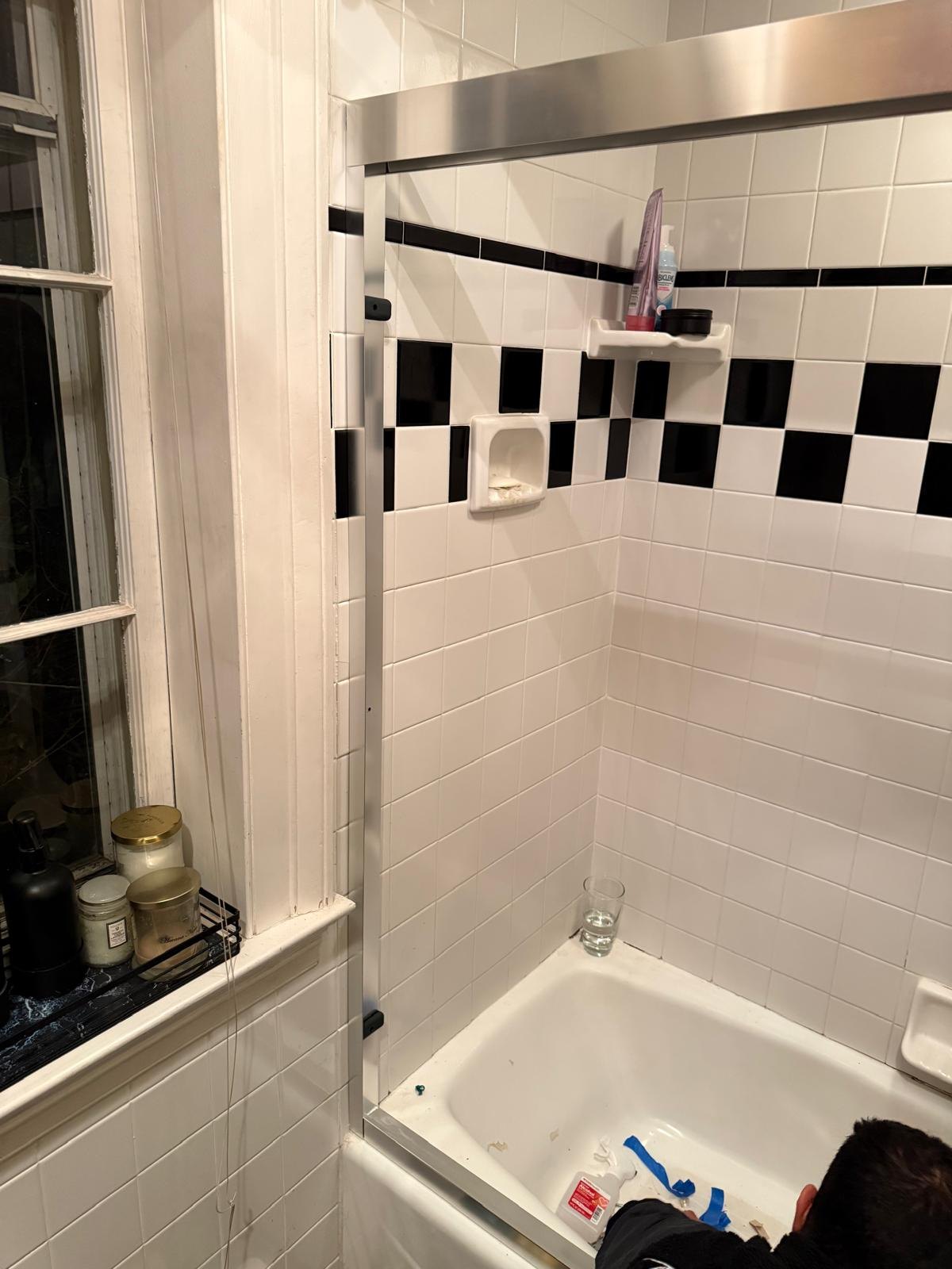 Another angle of sliding glass shower doors and tiled bath.