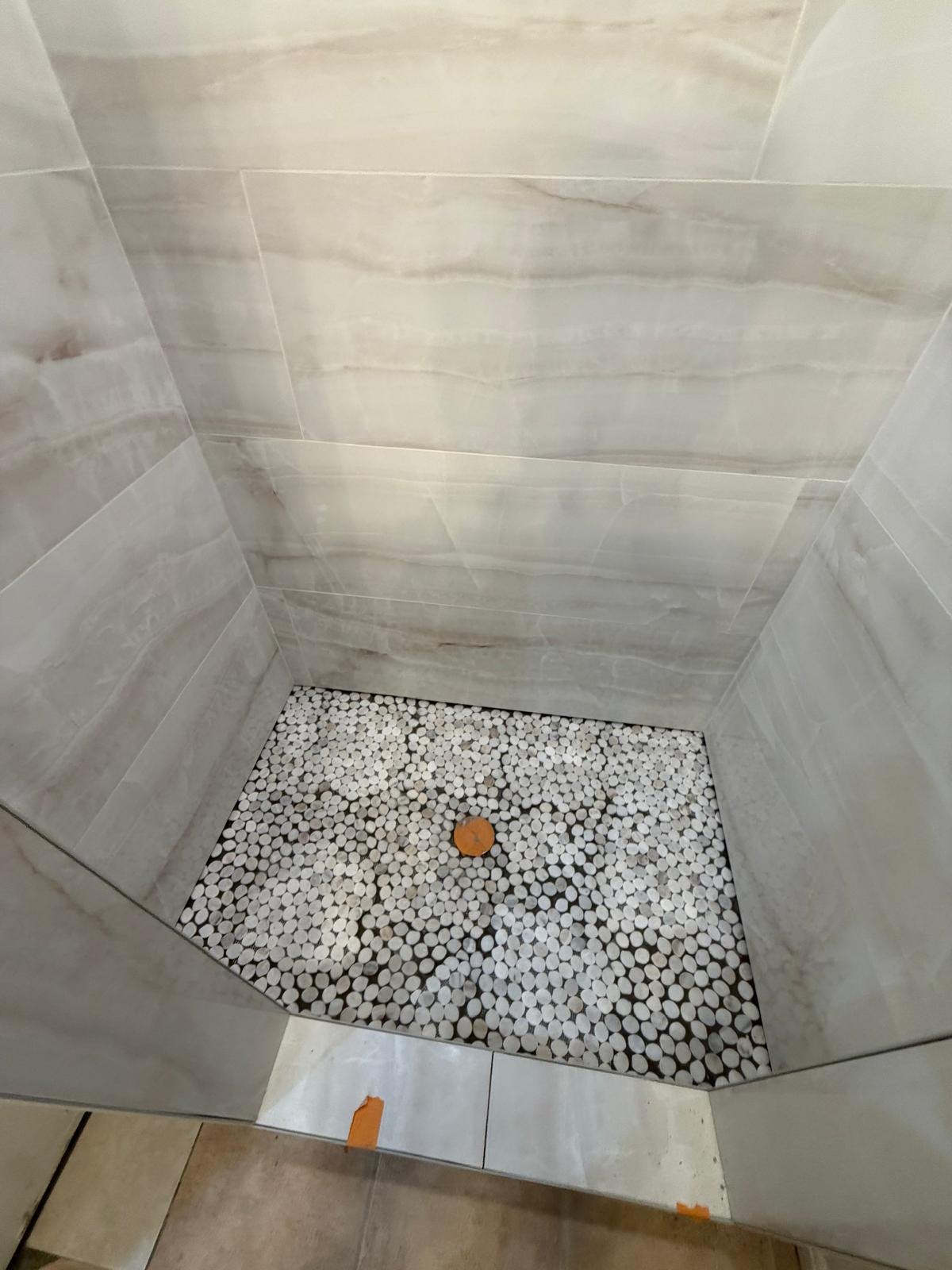 New light wall tiles and small-format shower floor tiles.