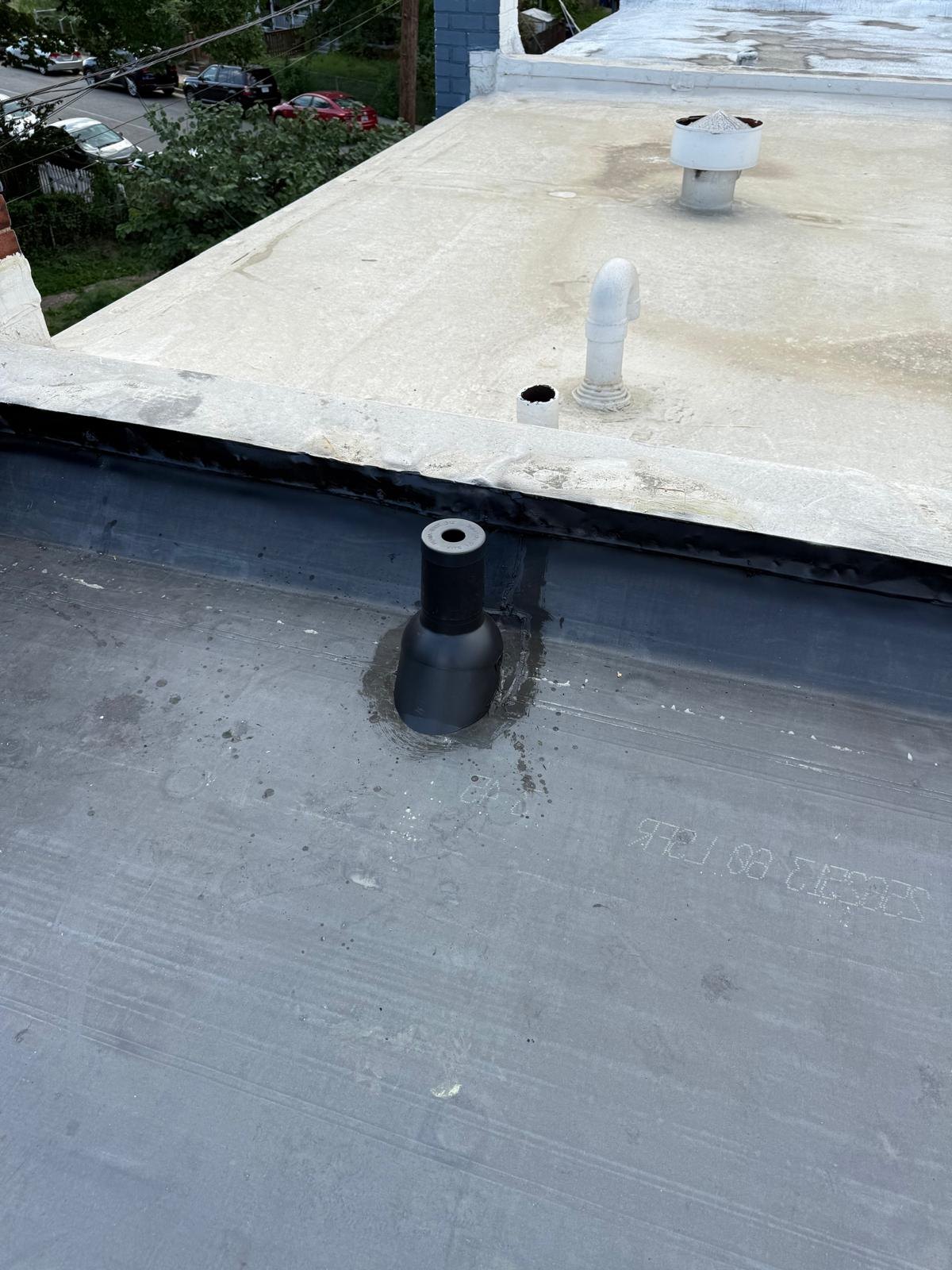 Closer view of the dark roof surface around a roof penetration.